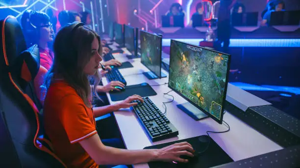 Photo of Pro Girl Plays Computer Game Plays RPG Strategy on a Championship. Diverse Esport Team of Pro Gamers Play in Mock-up Video Game. Stylish Neon Cyber Games Arena. Side View Shot