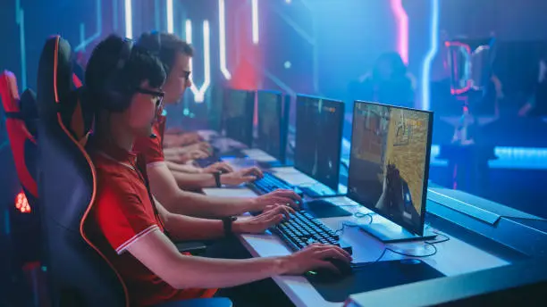 Diverse Esport Team of Pro Gamers Play in Mock-up FPS Shooter Video Game on a Championship. Stylish Neon Cyber Games Arena. Online Broadcasting of Tournament Event.