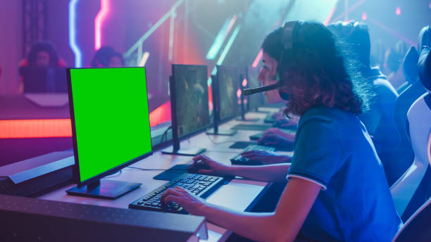 istock Pro Girl Plays Computer Video Game with Green Screen Display on Championship, Talking into Headset. Diverse Esport Team of Pro Gamers Play in Mock-up Video Game. Cyber Games Arena. Over the Shoulder 1357434561