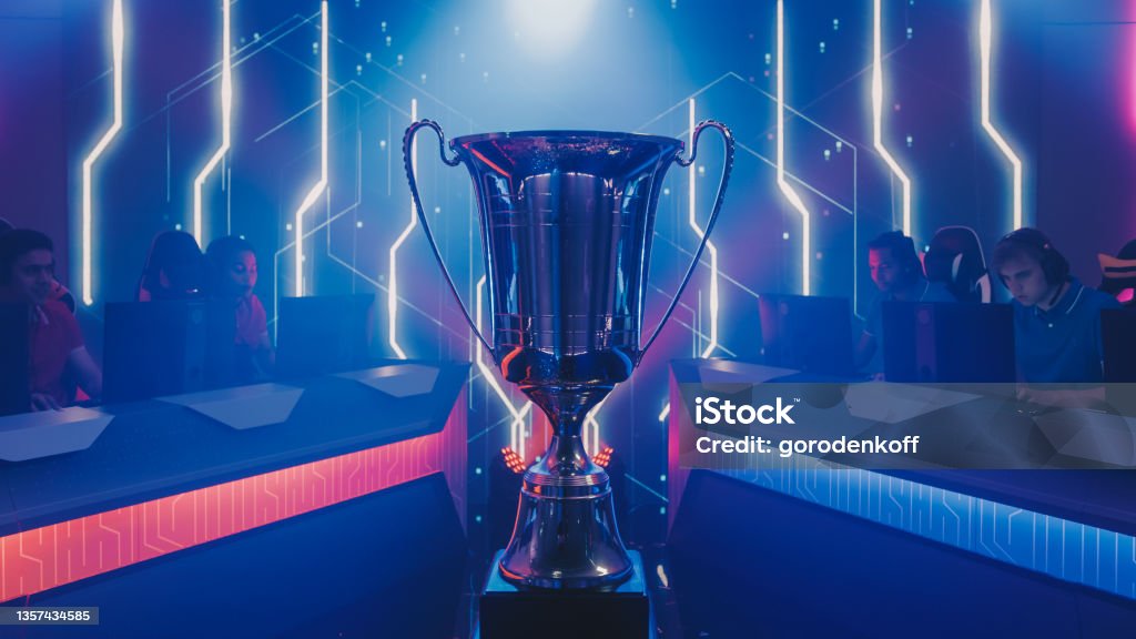 Two Esport Teams of Pro Gamers Play to Compete in Video Game on a Championship. Stylish Neon Cyber Games Online Streaming Tournament Arena with Trophy in the Center. Trophy - Award Stock Photo