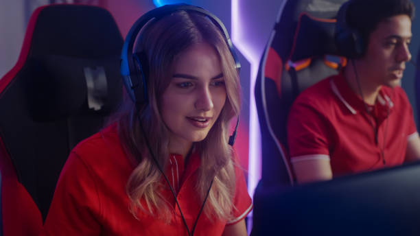 pro girl plays computer video game talking into headset with teammates on a championship. pro gamers. stylish neon cyber games online streaming tournament arena. portrait shot - esport audience bildbanksfoton och bilder