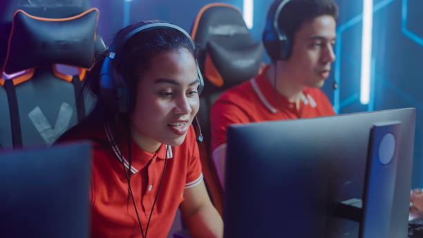 istock Pro Girl Plays Computer Video Game Talking into Headset with Teammates on a Championship. Diverse Esport Team of Gamers Playing in Cyber Games Arena. 1357434618