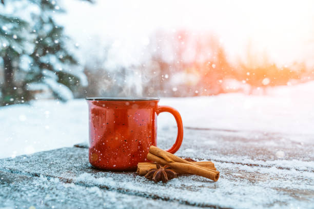 森の中の降雪中に木製の背景に熟したワインやお茶。シナモン、カルダモン、オレンジの香りスパイスを使った冬のホットドリンク。12月の自然とクリスマスの暖かさ、快適さと雰囲気 - mulled wine christmas tea heat ストックフォトと画像