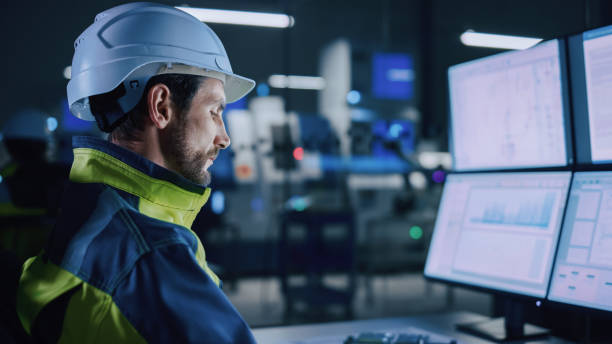 istock Industry 4.0 Modern Factory: Portrait of Facility Operator Controls Workshop Production Line, Uses Computer with Screens Showing Complex UI of Machine Operation Processes, Controllers 1357436599