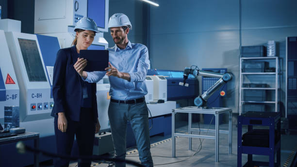 istock Portrait of Two Professional Engineers Use Industrial Digital Tablet to Work with Augmented Reality. Great Template Shot for Augmented Reality. Factory Workshop with CNC Machinery. 1357436673