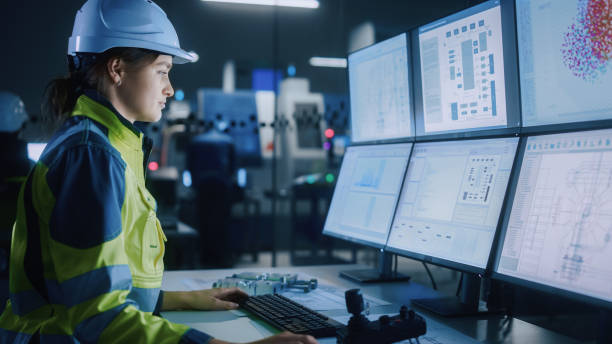 istock Industry 4.0 Modern Factory: Female Facility Operator Controls Workshop Production Line, Uses Computer with Screens Showing Complex UI of Machine Operation Processes, Controllers, Machinery Blueprints 1357436691