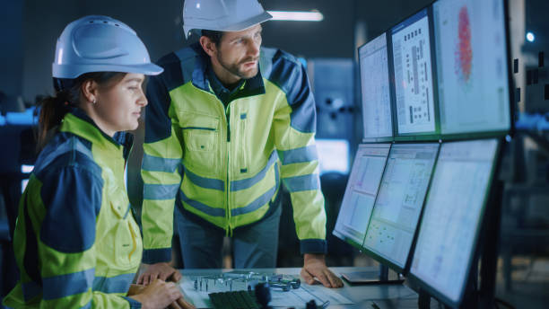 istock Industry 4.0 Modern Factory: Project Engineer Talks to Female Operator who Controls Facility Production Line, Uses Computer with Screens Showing AI, Machine Learning Enhanced Assembly Process 1357436777