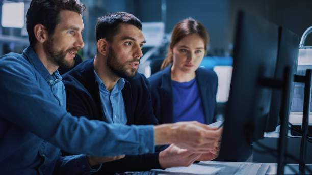 istock Industry 4.0 Modern Factory: Team of Innovative Industrial Engineers Use Computer and 3D Printer to Build Complex Component. Group of Scientists Use High-Tech Machinery for Futuristic Design 1357436807