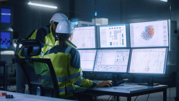 istock Industry 4.0 Modern Factory: Project Engineer Talks to Female Operator who Controls Facility Production Line, Uses Computer with Screens Showing AI, Machine Learning Enhanced Assembly Process 1357436815