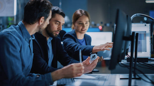 istock Industry 4.0 Modern Factory: Team of Innovative Industrial Engineers Use Computer and 3D Printer to Build Complex Component. Group of Scientists Use High-Tech Machinery for Futuristic Design 1357436822