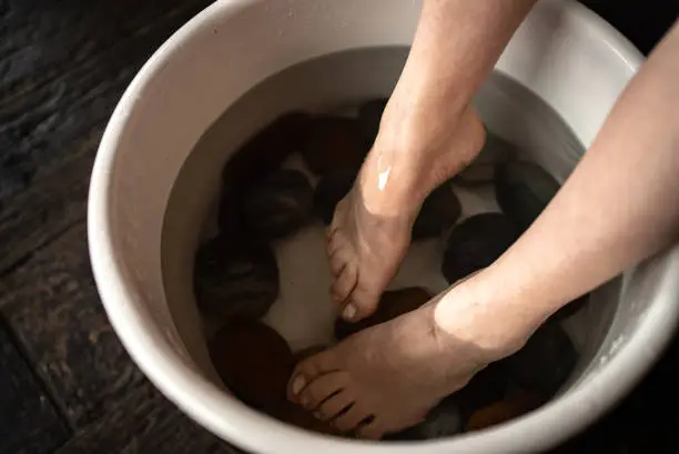 Feet of an adult woman doing foot therapy at a spa