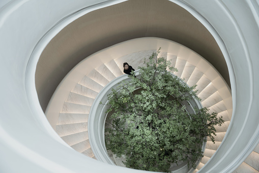 In the empty simple bright spiral staircase wearing black skirt Asian girl