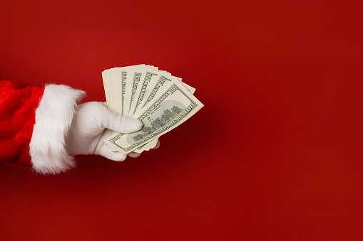 Santa Claus hand holding money on red background, copy space