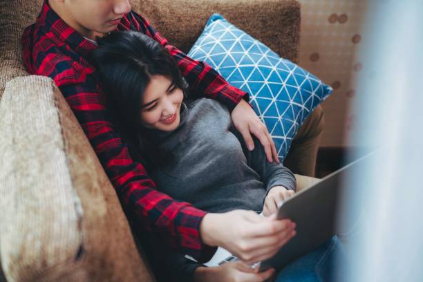istock asian couple relaxing using tablet computer on vacation together at home, People lifestyle concept. Christmas or anniversary. 1357442866