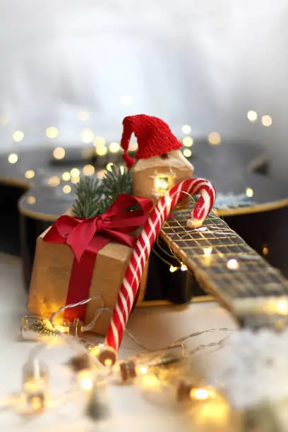 guitar surrounded by lights garlands with a present, gingerbread house and striped candy