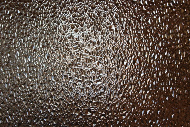istock Photograph close-up of glass embossed surface with refractive light uneven bumpy texture background 1357450155