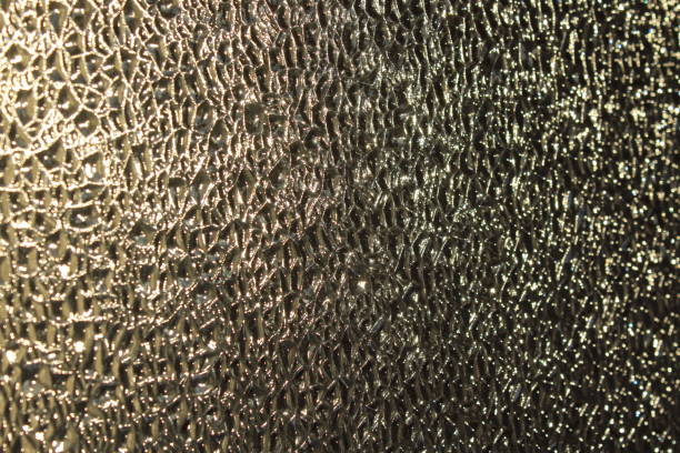 istock Photograph close-up of glass embossed surface with refractive light uneven bumpy texture background 1357450177