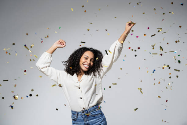 Beautiful excited woman at celebration party with falling confetti stock photo