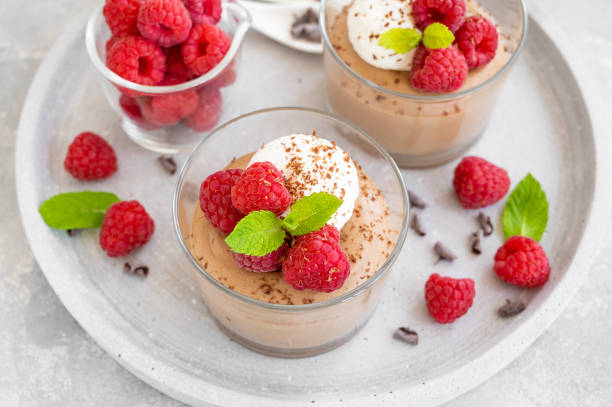 Chocolate mousse with whipped cream and fresh raspberries in a glass on a gray concrete background. Copy space. stock photo