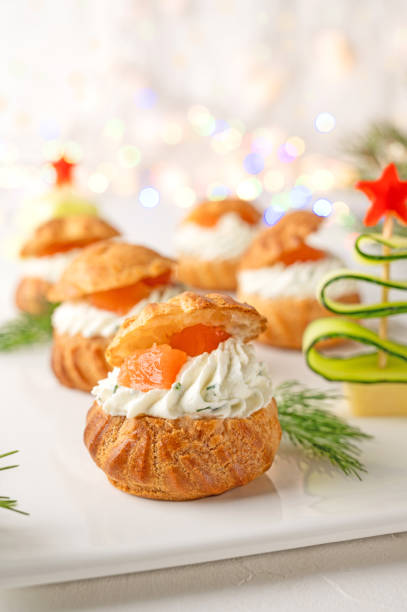 istock Festive savory profiteroles with salmon, cream cheese and dill on a white plate on a white background. Appetizer for Christmas and New Year. Selective focus. 1357455948