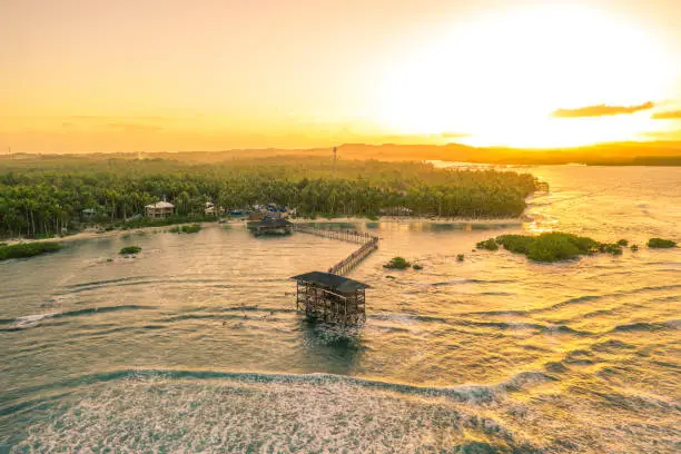 Aerial shot a sunset on wooden building in the middle of the waters of General Luna, Siargao Island, Philippines