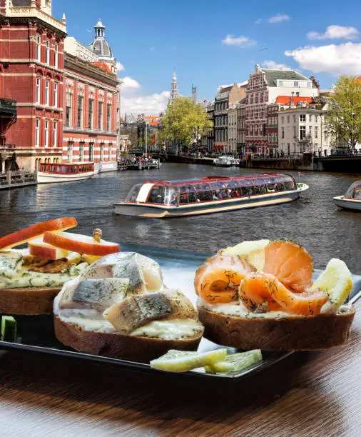 Amsterdam city with fishplate (salomon and codfish sandwiches) against tourboat on canal in Netherlands