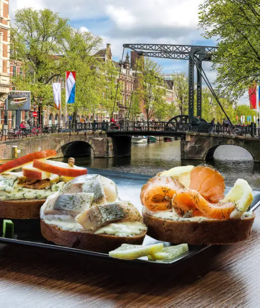 Amsterdam city with fishplate (salomon and codfish sandwiches) against tourboat on canal in Netherlands