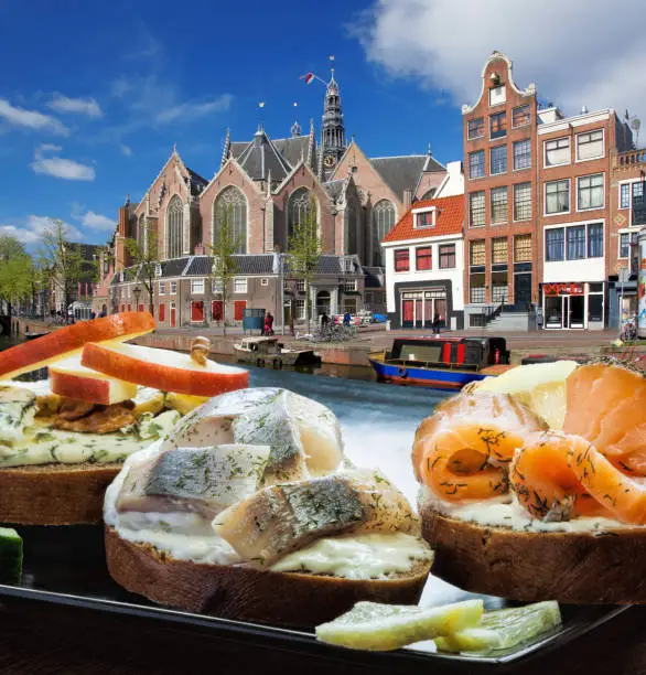 Amsterdam city with fishplate (salomon and codfish sandwiches) against tourboat on canal in Netherlands