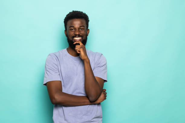 istock Young african man with hands on chin isolated on turquoise background 1357458563