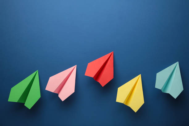 istock Color paper plane on blue background, Business competition concept. 1357460054