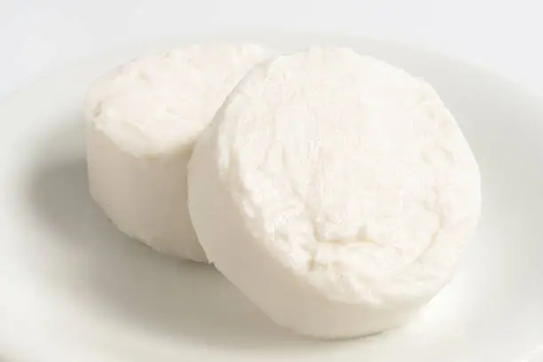 Two rounds of goat cheese on white ceramic plate.