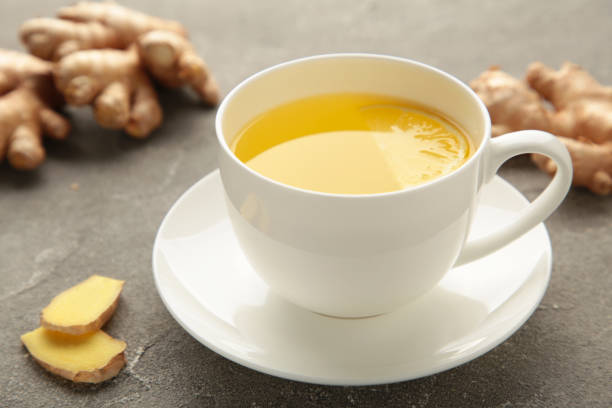 istock Ginger tea with lemon in a white cup on grey background. 1357460169