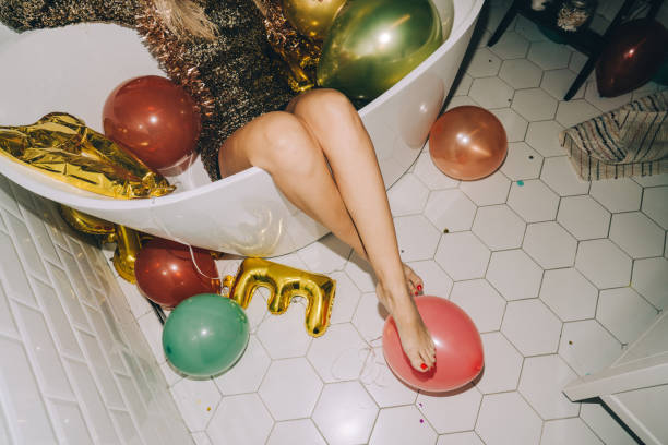 Afterparty Photo of a young woman sitting in a bathtub full of balloons after the great New Year's Eve party after party stock pictures, royalty-free photos & images