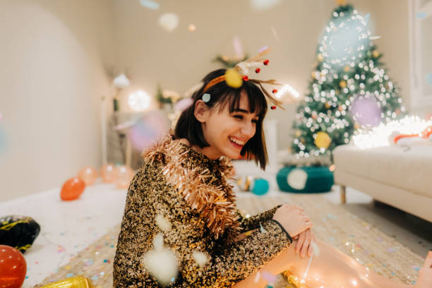 Smiling woman sitting on the floor while confetti is falling