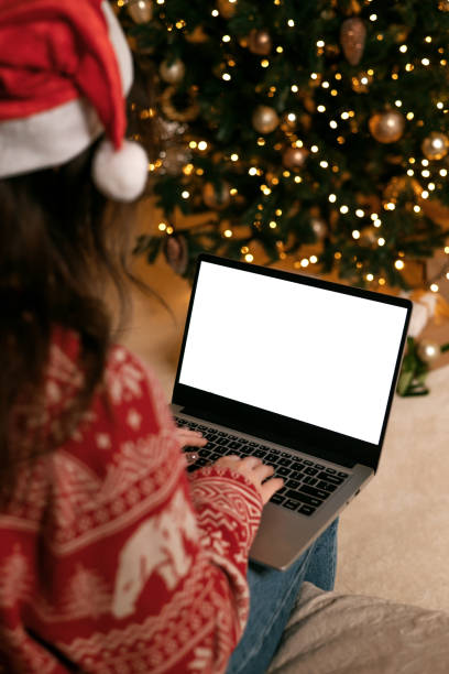 istock woman in santa hat working on laptop computer with blank display screen with mockup copy space. Concept of online shopping, discounts or online  communication at a distance 1357462241