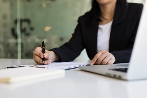 Business woman holding a pen to signing a document contract business agreement.