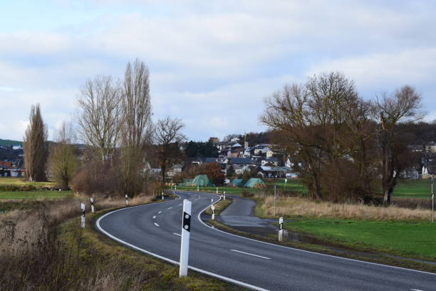 istock road curve between winter trees and a village in background 1357469932