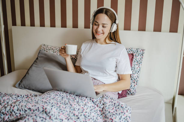 istock Young woman drinking morning coffee in bed and using laptop 1357472462