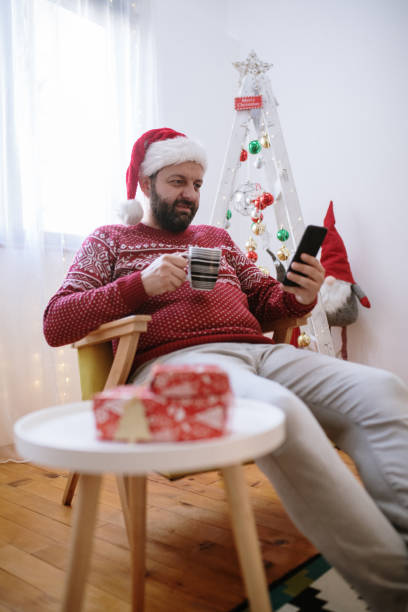 istock Modern young man using mobil phone at home for Christmas 1357474483