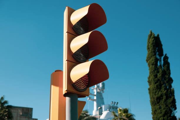 istock Traffic light with yellow light close-up on blue blurry sky background at daylight 1357476300