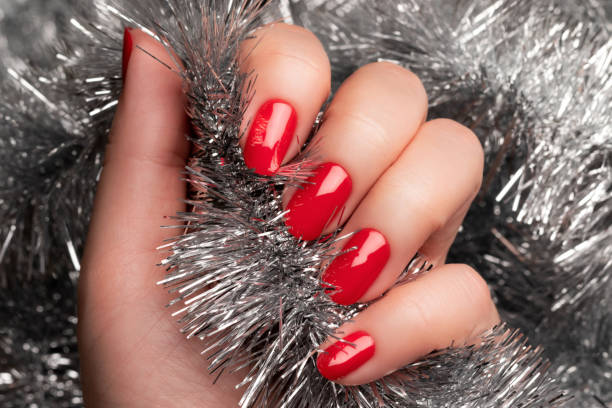 istock Hand with red nails with Christmas tinsel 1357478033