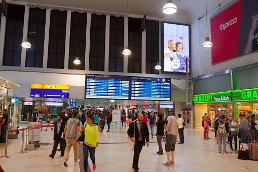 Entrance hall of main station Duesseldorf with people in summer night. People are walking in hall. In background are delay informations