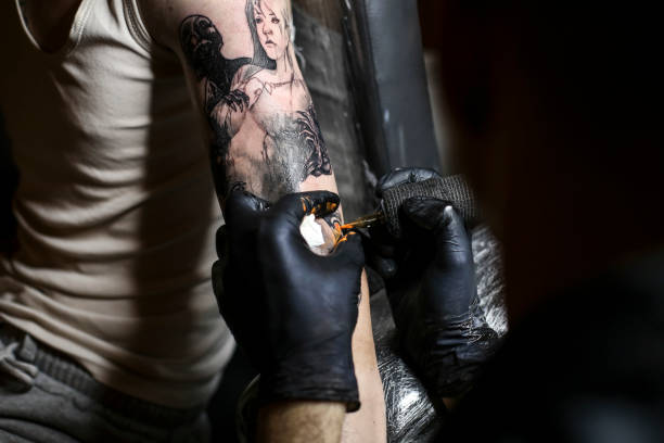 Sleeve tattoo Unrecognizable Caucasian young man getting a spooky horror tattoo on his arm. forearm tattoos men stock pictures, royalty-free photos & images