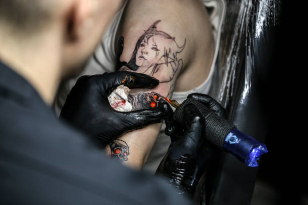 Tattoo artist at work Unrecognizable Caucasian young man getting a spooky horror tattoo on his arm. forearm tattoos men stock pictures, royalty-free photos & images
