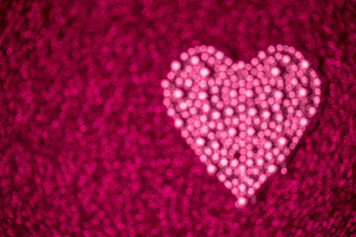 Glittering heart on a pink background. Beautiful bokeh, space for copy.