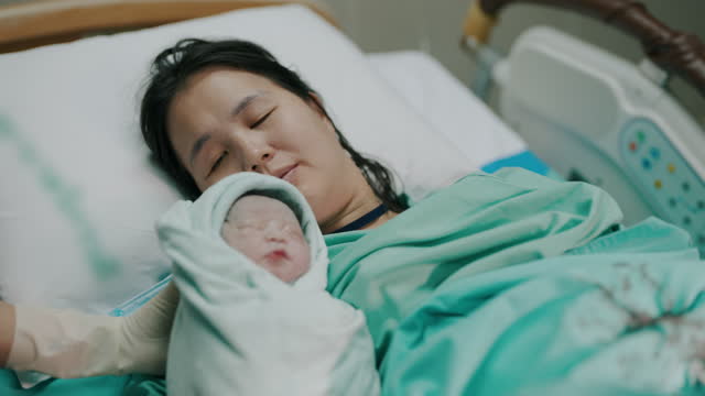 Asian mother and her baby were born in the delivery room at the hospital.