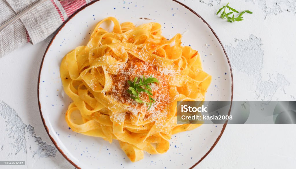 Fettuccine pasta with traditional Italian Passat sauce and parmesan cheese in light plate on old white concrete background. Top view. Above Stock Photo