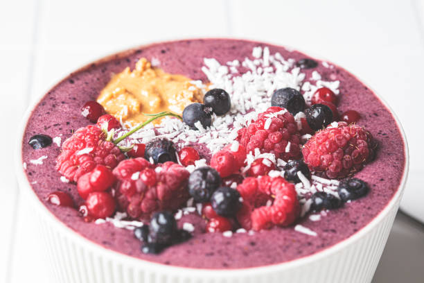 istock Berry smoothie bowl with raspberries, peanut butter and coconut on white tile background. Raw vegan food concept. 1357491639