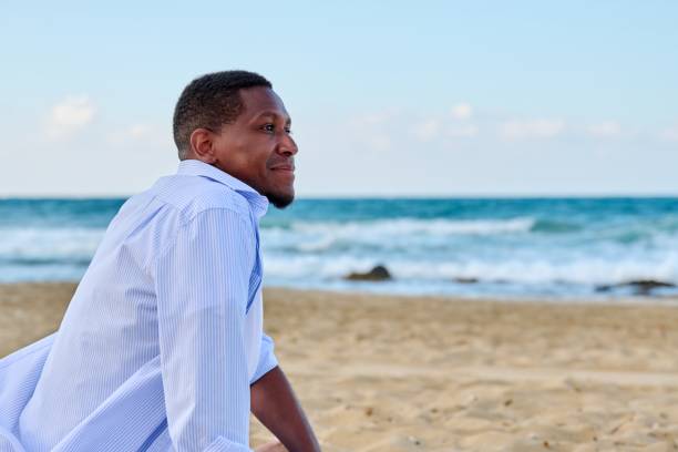 istock Young positive man looking in profile on the beach, copy space 1357492696
