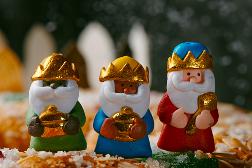 closeup of the three wise men, melchior, caspar and balthazar, on top of a roscon de reyes, the spanish three kings cake eaten traditionally on epiphany day